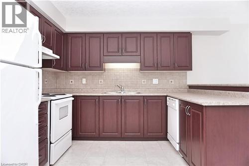 Kitchen featuring wood-finish cabinetry, light-toned countertops, and a tiled backsplash - 40 Madeleine Street, Kitchener, ON 
