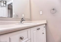 Bathroom vanity featuring white cabinetry with brushed nickel hardware, a light-toned countertop, and an integrated sink - 