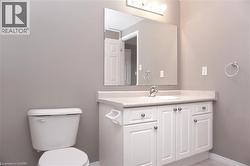 Bathroom featuring a white vanity with a single sink, an integrated countertop, and a large mirror - 