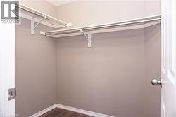 Walk-in closet featuring light gray walls, white shelving, and wood-finish flooring - 