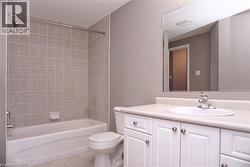 Bathroom featuring a white vanity with panel cabinetry and satin nickel hardware, an integrated sink with a chrome faucet, and a large wall-mounted mirror - 