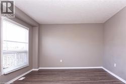 Spacious room featuring wood-finish flooring, neutral-toned walls, and a large window with horizontal blinds - 