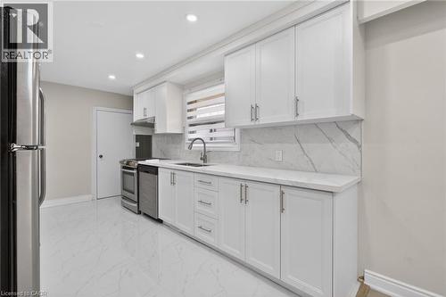 Kitchen featuring white shaker-style cabinetry, stainless steel appliances, a white marble-patterned backsplash, and a coordinating countertop - 53 Nicklin Crescent, Guelph, ON - Indoor Photo Showing Kitchen