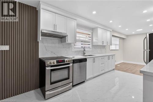 Contemporary kitchen featuring white cabinetry, stainless steel appliances, a white stone-look backsplash, and integrated ceiling lighting - 53 Nicklin Crescent, Guelph, ON - Indoor Photo Showing Kitchen With Stainless Steel Kitchen