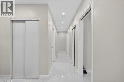 Long hallway featuring recessed lighting, light-colored walls, white baseboards, and glossy white flooring - 53 Nicklin Crescent, Guelph, ON - Indoor Photo Showing Other Room