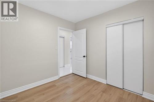 Room featuring wood-finish flooring, light-toned walls, white baseboards, and a white sliding closet door - 53 Nicklin Crescent, Guelph, ON - Indoor Photo Showing Other Room