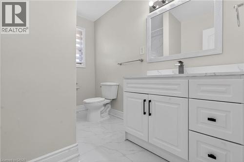 White vanity with black hardware, a rectangular mirror, and a modern single-handle faucet, set against light-toned walls and marble-look floor tiling - 53 Nicklin Crescent, Guelph, ON - Indoor Photo Showing Bathroom