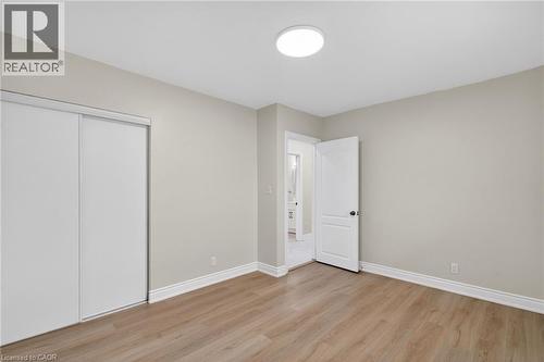 Neutral-toned room featuring light wood-finish flooring, white baseboards, and a contemporary ceiling light fixture - 53 Nicklin Crescent, Guelph, ON - Indoor Photo Showing Other Room