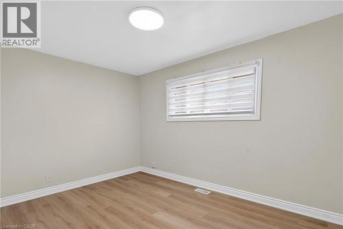 Neutral-toned room featuring wood-finish flooring, a contemporary flush-mount ceiling light, white baseboards, and a window with horizontal blinds - 53 Nicklin Crescent, Guelph, ON - Indoor Photo Showing Other Room