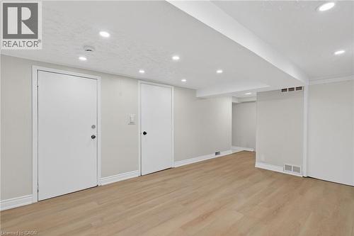 Spacious room featuring light wood-finish flooring, recessed lighting, neutral wall paint, white trim, and two white doors - 53 Nicklin Crescent, Guelph, ON - Indoor
