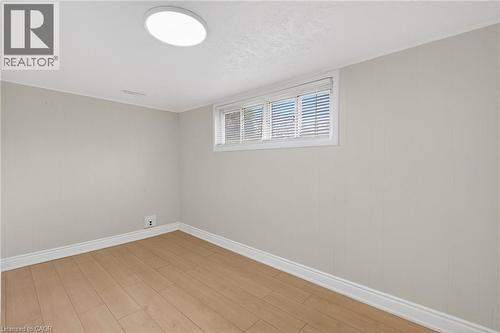 Room featuring wood-finish flooring, a window with horizontal blinds, light-toned wall paneling, white baseboards, and a flush-mount ceiling light fixture - 53 Nicklin Crescent, Guelph, ON - Indoor Photo Showing Other Room