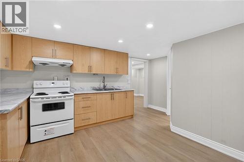 Kitchen featuring wood-finish cabinetry, light-toned countertops, and a white electric range with overhead ventilation - 53 Nicklin Crescent, Guelph, ON - Indoor Photo Showing Kitchen With Double Sink