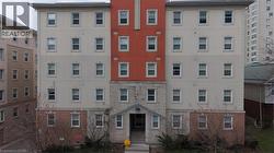 Multi-story building featuring a brick base, stone facade, and stucco exterior with contrasting red and beige sections - 