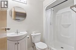 Bathroom featuring a white vanity with integrated sink, chrome faucet, and a wall-mounted circular mirror - 