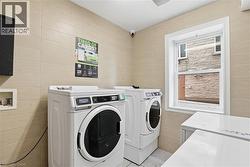 Dedicated laundry area featuring beige tiled walls and light-colored flooring - 