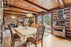 Dining area featuring exposed log walls, a wood-plank ceiling, and light wood-finish flooring - 