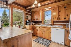 Rustic kitchen featuring wood cabinetry, a built-in dishwasher, and a wood-finish countertop - 