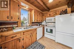Kitchen featuring wood-finish cabinetry, tile countertops, a double basin stainless steel sink, and wood-finish flooring - 