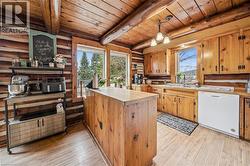 Kitchen featuring log walls and ceiling, wood-finish flooring, a wood island, wood cabinetry, and a double basin sink - 