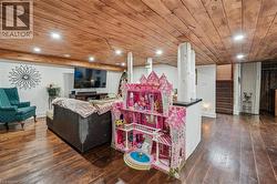 Spacious room featuring wood-finish flooring, a wood-paneled ceiling with recessed lighting, and white walls - 