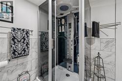 Enclosed shower cabin featuring multiple body jets, an overhead rainfall shower, a handheld showerhead, and an integrated seat - 