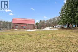 Brown barn structure with a red metal roof, featuring a small attached lean-to - 