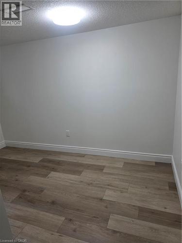 Room featuring wood-finish flooring, white baseboards, light neutral wall paint, and a flush-mount ceiling light - 22 Montrose Avenue, Kitchener, ON - Indoor Photo Showing Other Room