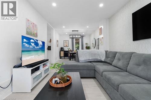Spacious living area featuring light wood-finish flooring, recessed lighting, and a textured accent wall - 133 Frederick Avenue, Hamilton, ON - Indoor Photo Showing Living Room