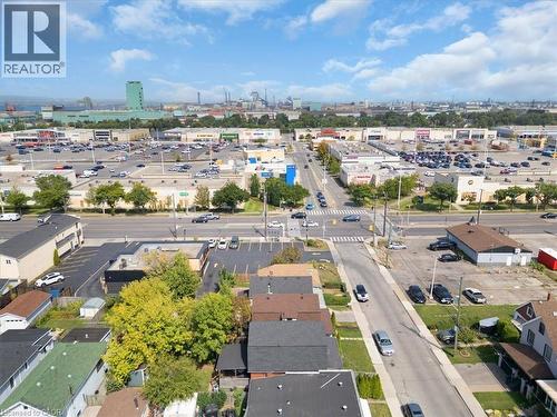 Aerial perspective showcasing a residential street with diverse housing styles, mature trees, and a commercial corridor in the background - 133 Frederick Avenue, Hamilton, ON - Outdoor With View