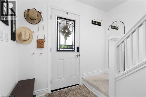 Entryway featuring a white paneled door with decorative glass insert, bright white walls, an arched built-in detail, and a carpeted staircase with white balusters - 133 Frederick Avenue, Hamilton, ON - Indoor Photo Showing Other Room