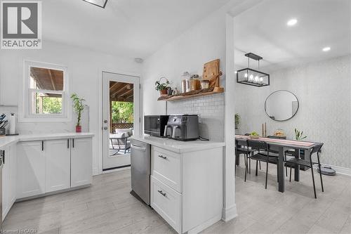 White kitchen cabinetry with sleek black hardware, quartz countertops, and a subway tile backsplash - 133 Frederick Avenue, Hamilton, ON - Indoor Photo Showing Kitchen
