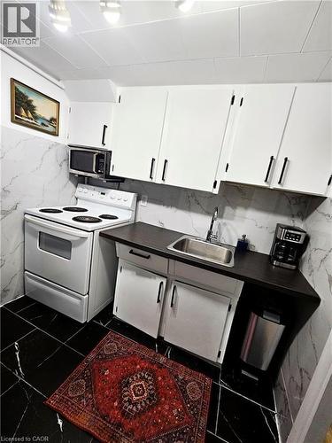 Kitchen featuring white cabinetry with dark hardware, a stainless steel sink, and dark countertops - 34 Christopher Drive, Cambridge, ON - Indoor Photo Showing Kitchen