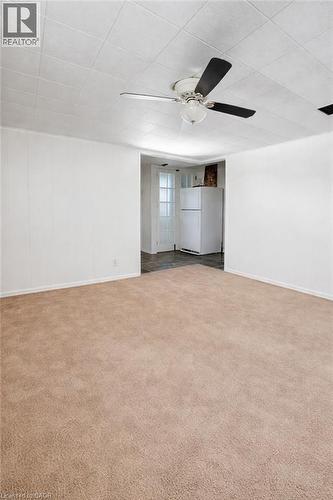 Spacious carpeted room featuring a ceiling fan with integrated lighting, white panel walls, and a dropped ceiling - 34 Christopher Drive, Cambridge, ON - Indoor Photo Showing Other Room
