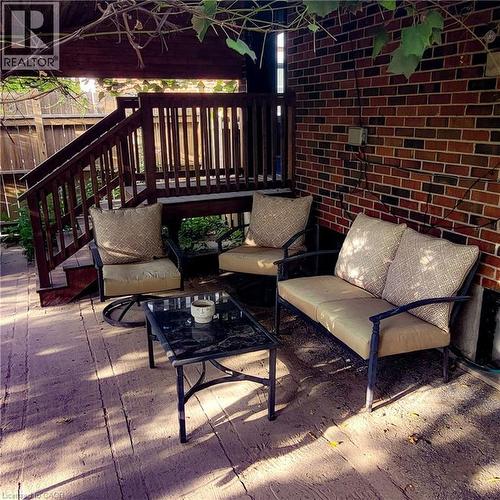 Covered outdoor patio featuring a wood-finish deck and brick exterior wall - 34 Christopher Drive, Cambridge, ON - Outdoor With Deck Patio Veranda With Exterior