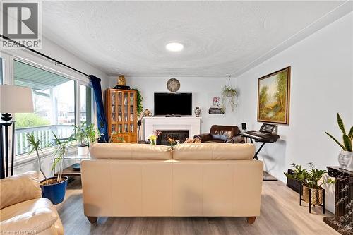 Spacious living area featuring light wood-finish flooring, a white-painted fireplace with mantel, and a built-in recessed ceiling light - 34 Christopher Drive, Cambridge, ON - Indoor Photo Showing Living Room With Fireplace