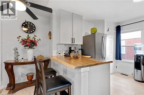 Kitchen featuring a natural wood-finish countertop, white cabinetry with dark hardware, white subway tile backsplash, and light wood-finish flooring - 34 Christopher Drive, Cambridge, ON - Indoor Photo Showing Kitchen