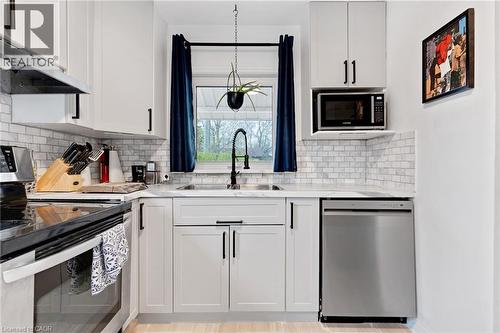 Modern kitchen featuring white shaker cabinetry with black hardware, subway tile backsplash, stainless steel appliances, and a double basin sink with a gooseneck faucet - 34 Christopher Drive, Cambridge, ON - Indoor Photo Showing Kitchen With Double Sink With Upgraded Kitchen