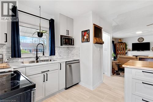Modern kitchen featuring light gray cabinetry with black hardware, subway tile backsplash, stainless steel sink with gooseneck faucet, and integrated stainless steel dishwasher - 34 Christopher Drive, Cambridge, ON - Indoor Photo Showing Kitchen With Double Sink