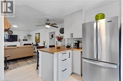 Kitchen featuring wood-finish countertops, white shaker cabinetry with black hardware, and a subway tile backsplash - 34 Christopher Drive, Cambridge, ON - Indoor Photo Showing Kitchen