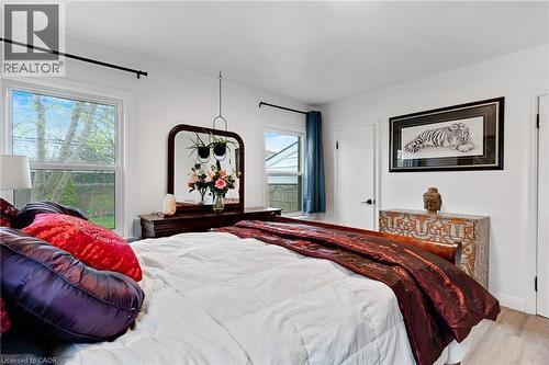 Bright room featuring two windows, a wood-finish dresser with a framed mirror, and light wood-finish flooring - 34 Christopher Drive, Cambridge, ON - Indoor Photo Showing Bedroom