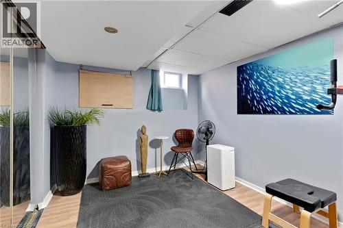 Recessed lighting illuminates this versatile space featuring wood-finish flooring, a wall-mounted display, and a large mirrored wall - 34 Christopher Drive, Cambridge, ON - Indoor Photo Showing Other Room