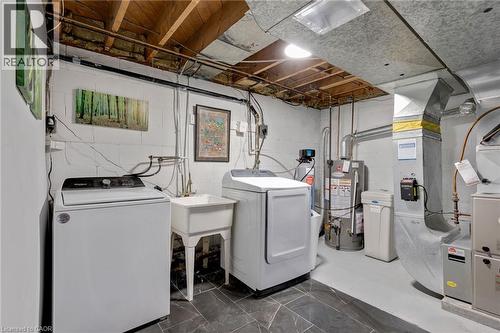 Utility area featuring a laundry sink, water heater, water treatment system, and HVAC components - 34 Christopher Drive, Cambridge, ON - Indoor Photo Showing Laundry Room