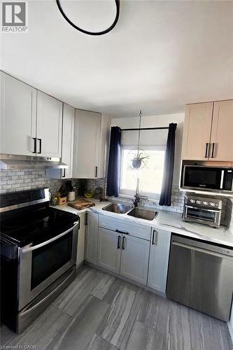 Modern kitchen featuring light cabinetry, stainless steel appliances, a tile backsplash, and stone-look flooring - 34 Christopher Drive, Cambridge, ON - Indoor Photo Showing Kitchen With Double Sink