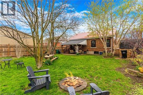 Spacious backyard featuring a lush green lawn, mature trees, and a built-in fire pit - 34 Christopher Drive, Cambridge, ON - Outdoor