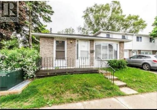 Brick facade residence featuring a front porch with wrought iron railing, a prominent bay window, and a sloped grass lawn - 744 Parkview Crescent, Cambridge, ON - Outdoor