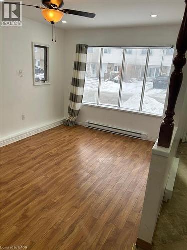 Spacious room featuring wood-finish flooring, a large multi-pane window, and a ceiling fan with integrated lighting - 744 Parkview Crescent, Cambridge, ON - Indoor Photo Showing Other Room