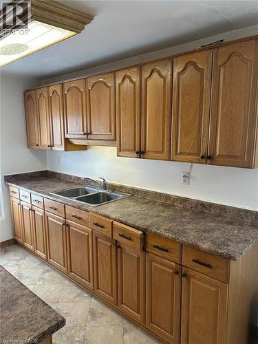 Kitchen featuring extensive wood cabinetry with dark hardware, a double-basin stainless steel sink, and speckled countertops - 744 Parkview Crescent, Cambridge, ON - Indoor Photo Showing Kitchen With Double Sink