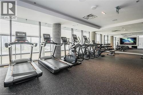 Fitness center featuring cardio equipment, strength training machines, free weights, a large display screen, and resilient rubber flooring - 5 Wellington Street S Unit# 904, Kitchener, ON - Indoor Photo Showing Gym Room