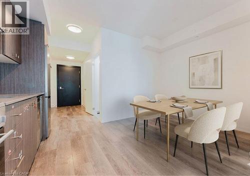 Expansive wood-finish flooring extends throughout the space, complementing the dark wood-grain cabinetry and light countertops - 5 Wellington Street S Unit# 904, Kitchener, ON - Indoor Photo Showing Dining Room
