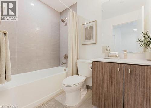 Bathroom featuring a full-size tub with tile surround, a built-in toilet, a vanity with a white countertop, wood-finish cabinetry, and a large wall-mounted mirror - 5 Wellington Street S Unit# 904, Kitchener, ON - Indoor Photo Showing Bathroom